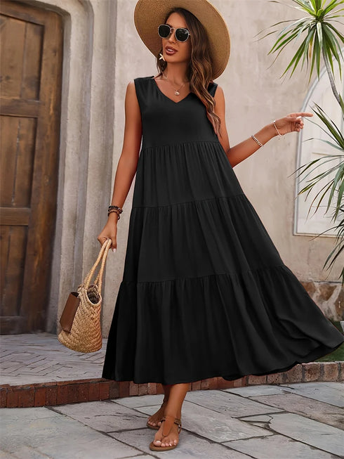 Woman wearing a black dress and straw hat standing outdoors.